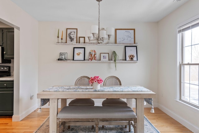 dining area featuring a wealth of natural light, a notable chandelier, baseboards, and wood finished floors