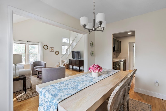 dining room with light wood-style flooring, a chandelier, stairway, and baseboards