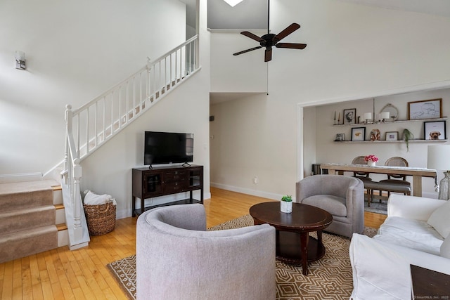 living area with hardwood / wood-style flooring, a towering ceiling, baseboards, and stairs