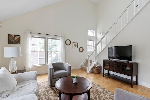 living area featuring light wood-type flooring, baseboards, and stairs