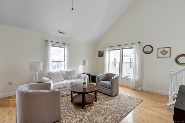 living area featuring light wood-style floors, visible vents, stairway, and baseboards