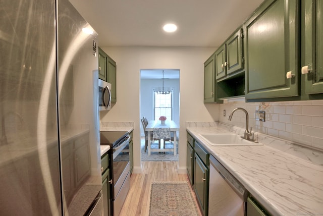 kitchen with green cabinets, stainless steel appliances, tasteful backsplash, and a sink