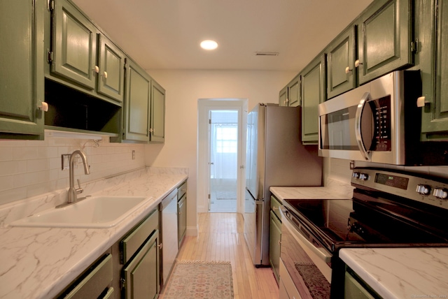 kitchen with a sink, stainless steel appliances, open shelves, and green cabinetry