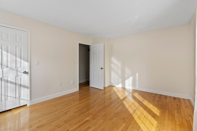 unfurnished bedroom with hardwood / wood-style flooring and baseboards