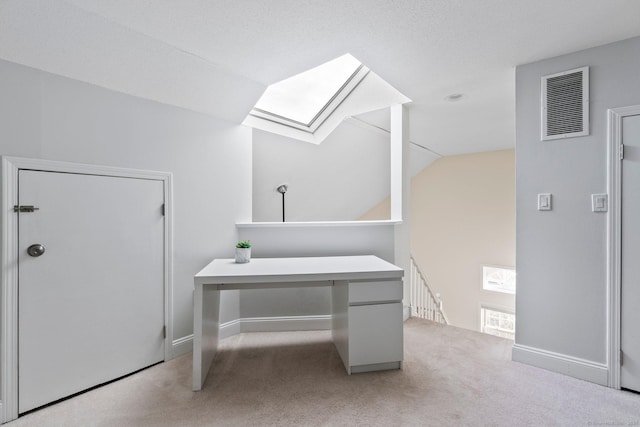 office space featuring lofted ceiling with skylight, visible vents, light carpet, and baseboards