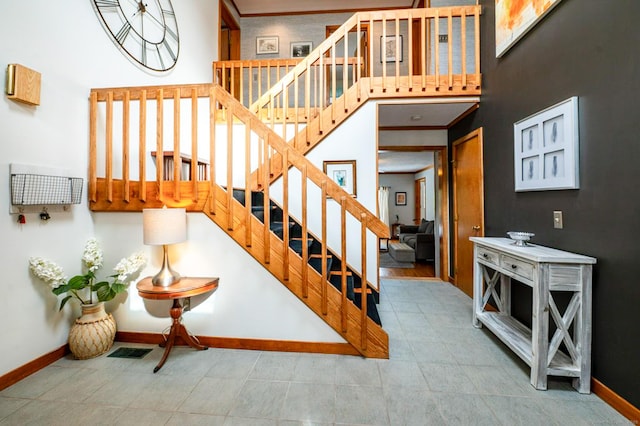 stairs with visible vents, a towering ceiling, and baseboards