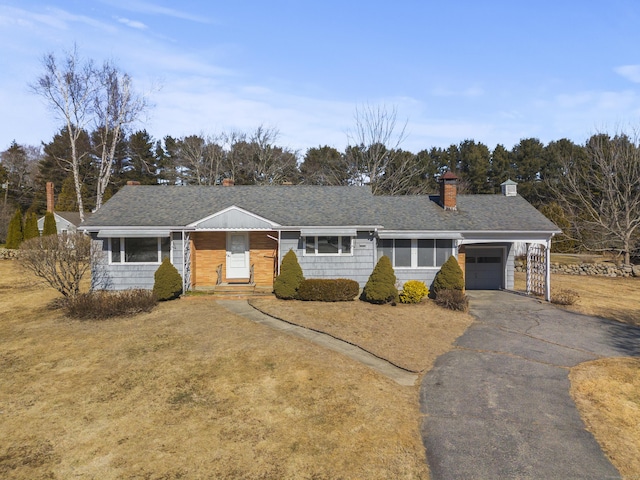 ranch-style home featuring aphalt driveway, a front lawn, a garage, and roof with shingles