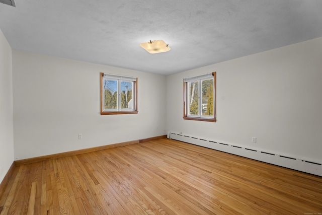 unfurnished room featuring light wood-style flooring, baseboards, and baseboard heating