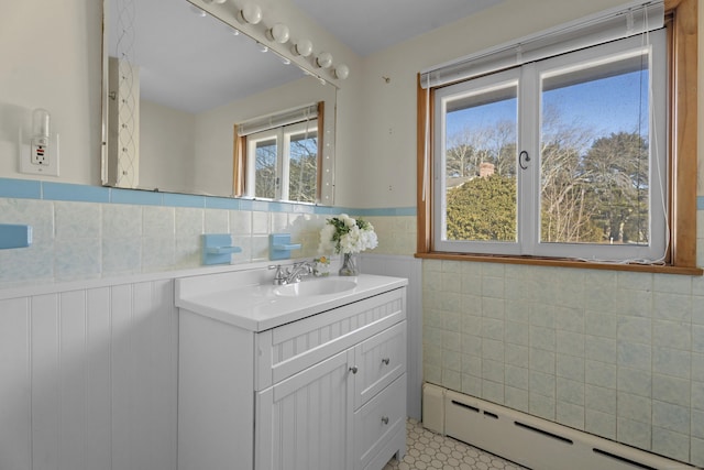 bathroom featuring a baseboard heating unit, wainscoting, tile walls, and vanity