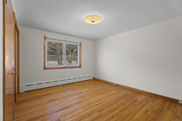 spare room with light wood-type flooring, baseboards, and baseboard heating