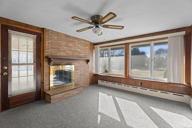 unfurnished living room with a baseboard radiator, a fireplace, ceiling fan, and carpet flooring