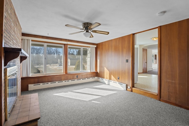 carpeted spare room with a baseboard heating unit, arched walkways, wooden walls, and a ceiling fan