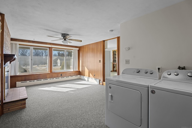 washroom featuring washer and clothes dryer, a ceiling fan, baseboard heating, carpet flooring, and wood walls