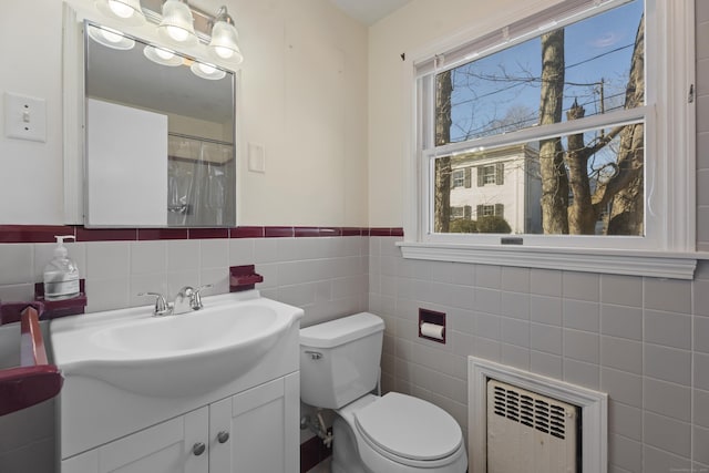 bathroom featuring tile walls, toilet, vanity, and radiator heating unit