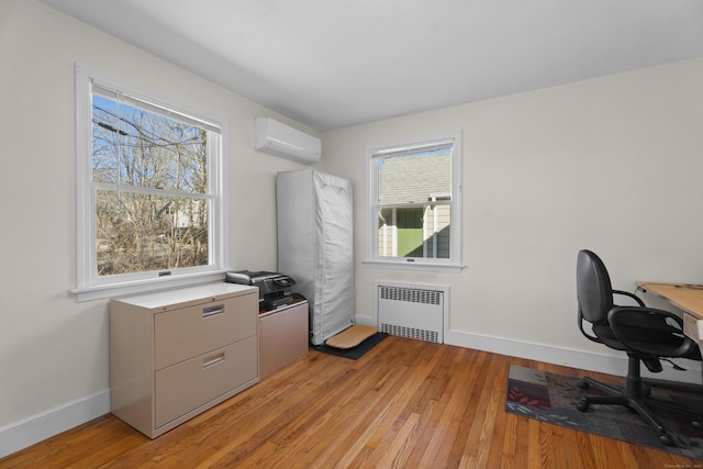 office space featuring baseboards, an AC wall unit, radiator heating unit, and light wood-style floors