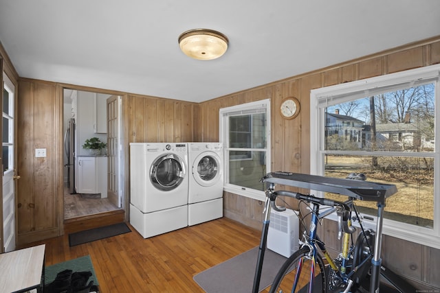 laundry area with laundry area, wood finished floors, wood walls, and washing machine and clothes dryer