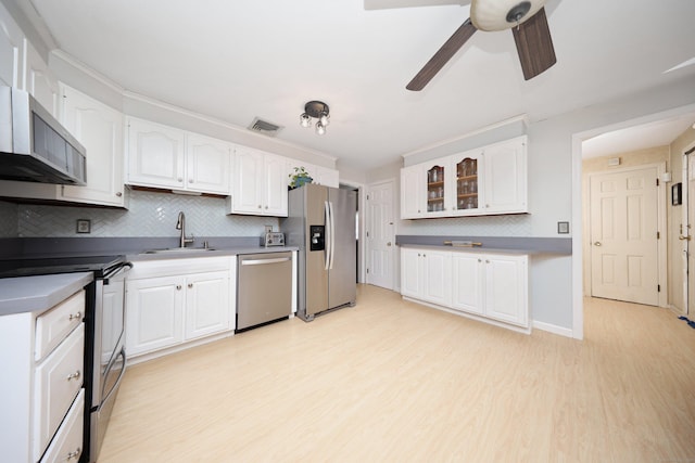 kitchen with sink, light wood-type flooring, appliances with stainless steel finishes, white cabinets, and backsplash