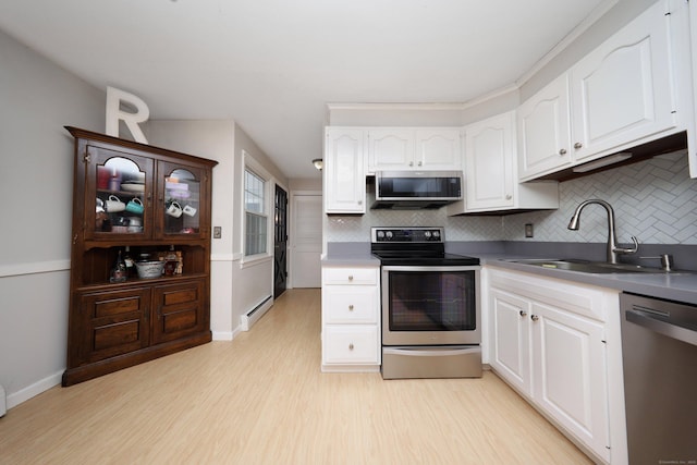 kitchen featuring appliances with stainless steel finishes, a baseboard heating unit, sink, and white cabinets