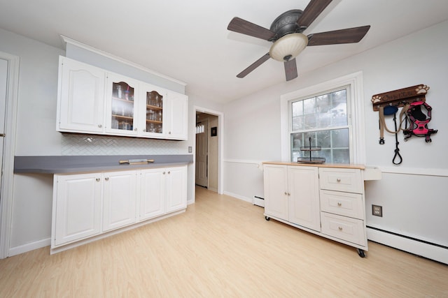 kitchen featuring backsplash, baseboard heating, light hardwood / wood-style floors, and white cabinets