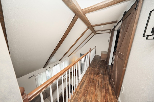 corridor with dark wood-type flooring, lofted ceiling with beams, and a barn door