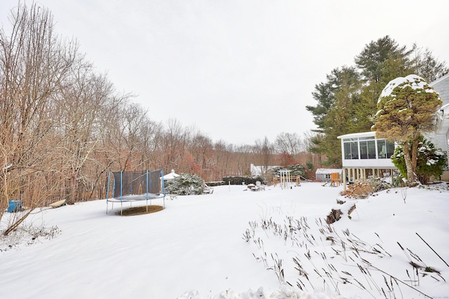 yard covered in snow with a trampoline and a sunroom