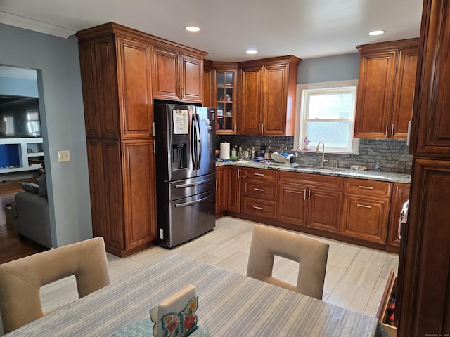 kitchen with sink, backsplash, stainless steel fridge, and light stone counters