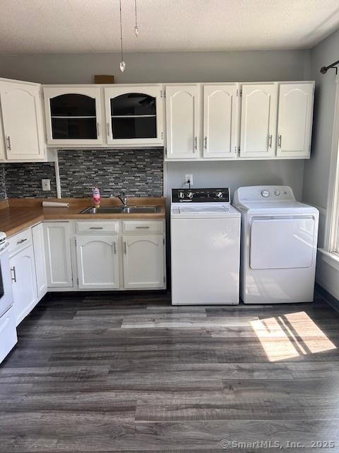 laundry room featuring dark wood-type flooring, sink, washing machine and dryer, and a textured ceiling