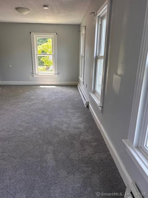 spare room with baseboard heating, carpet flooring, and a textured ceiling