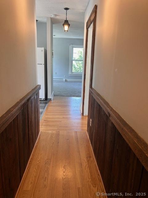 corridor featuring baseboard heating and light hardwood / wood-style flooring