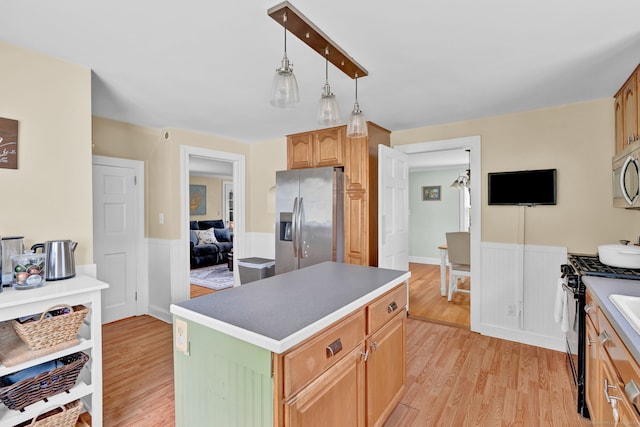 1379 Old N Colony Rd, Meriden, CT 06450 - kitchen with stainless steel appliances, light wood-type flooring, wainscoting, and a kitchen island
