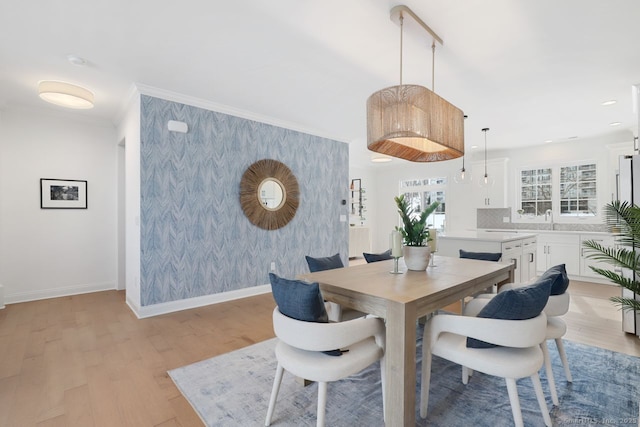 dining room with sink, crown molding, and light wood-type flooring