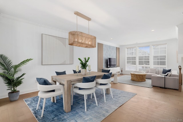 dining space featuring crown molding and light hardwood / wood-style flooring