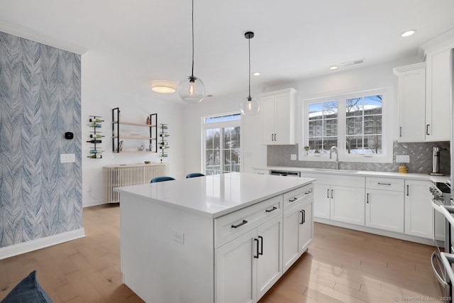 kitchen with white cabinetry, hanging light fixtures, a center island, decorative backsplash, and light wood-type flooring