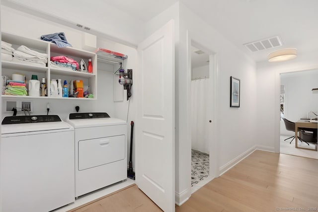 clothes washing area with washing machine and dryer and light hardwood / wood-style floors