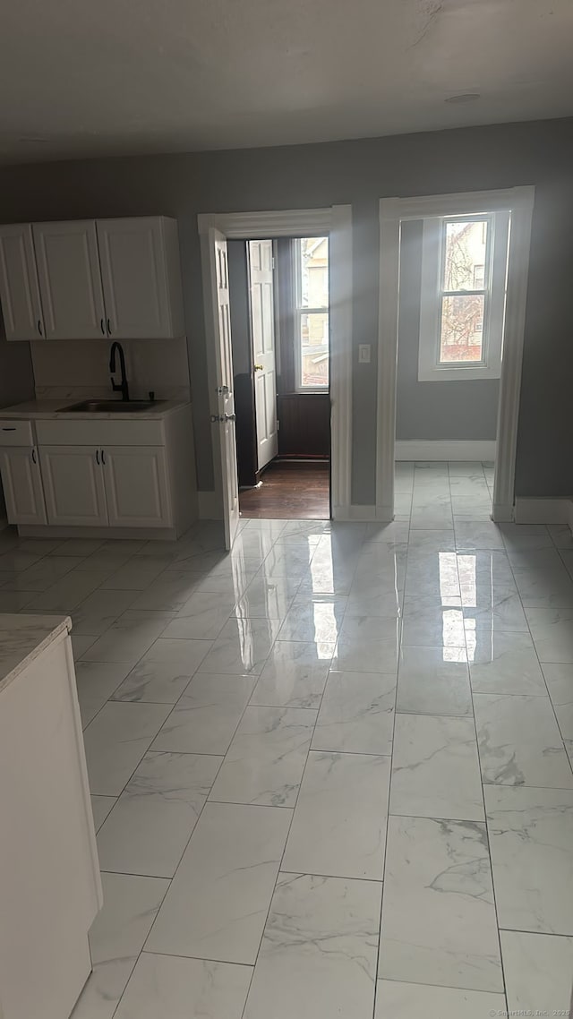 unfurnished dining area with a sink, baseboards, and marble finish floor