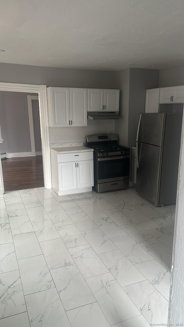 kitchen featuring stainless steel appliances, light countertops, under cabinet range hood, a textured ceiling, and marble finish floor