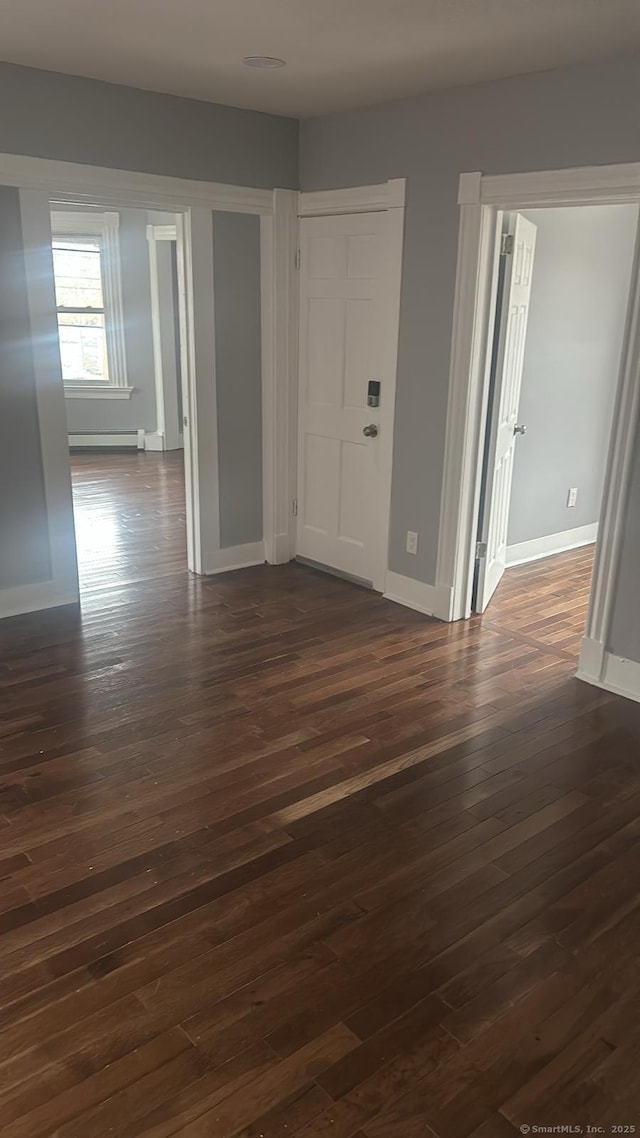 empty room with baseboards, baseboard heating, and dark wood-style flooring