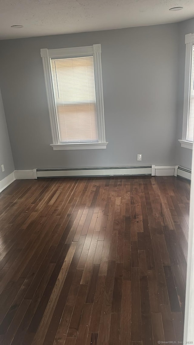 unfurnished room featuring a baseboard radiator, baseboards, and dark wood-type flooring