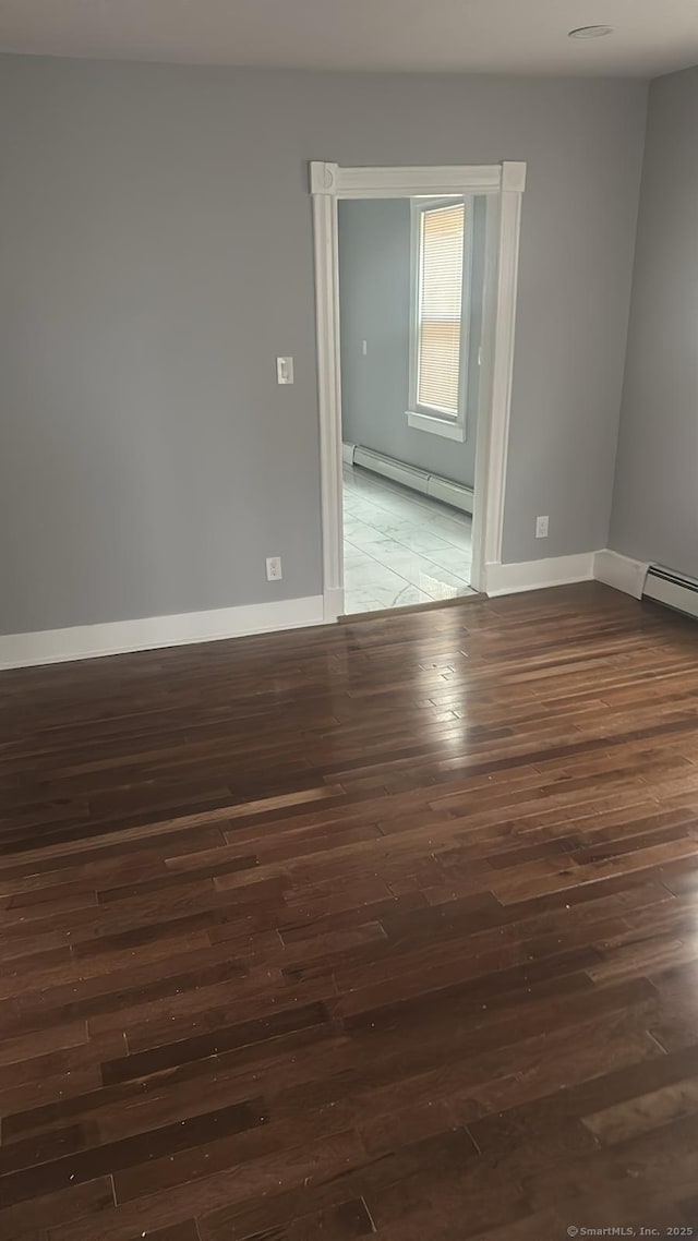 unfurnished room featuring dark wood finished floors, baseboards, and baseboard heating