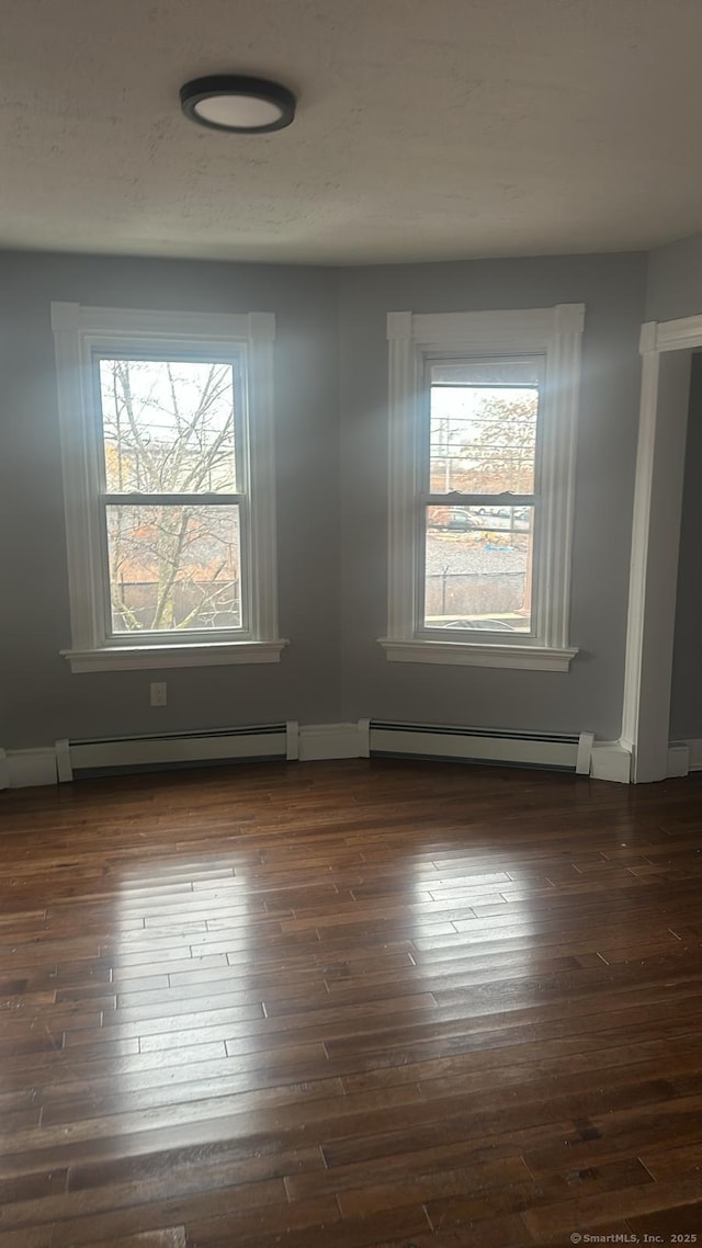 spare room featuring dark wood finished floors and baseboard heating