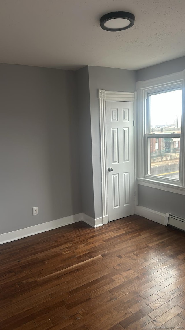 unfurnished room with dark wood-type flooring and baseboards