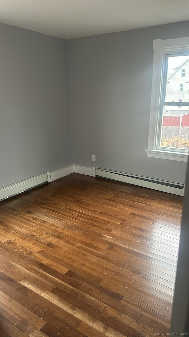 unfurnished room with dark wood-type flooring and a baseboard radiator