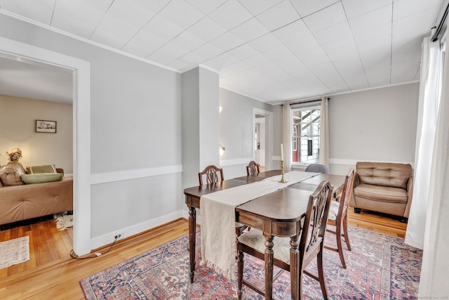 dining space with crown molding and wood-type flooring