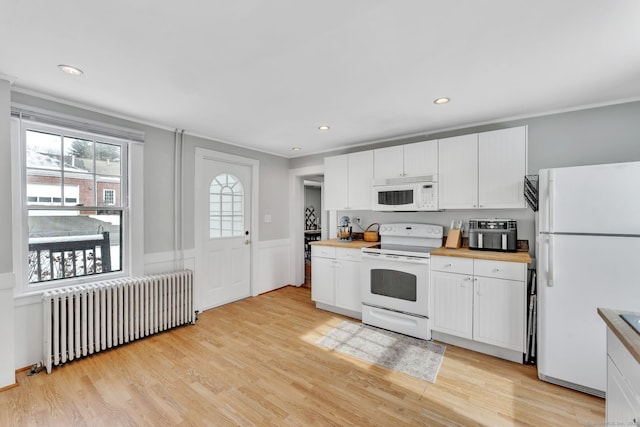 kitchen featuring radiator, white appliances, light hardwood / wood-style floors, and white cabinets