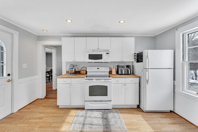 kitchen featuring crown molding, white appliances, light wood-type flooring, and white cabinets