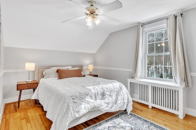 bedroom with hardwood / wood-style flooring, radiator heating unit, ceiling fan, and vaulted ceiling