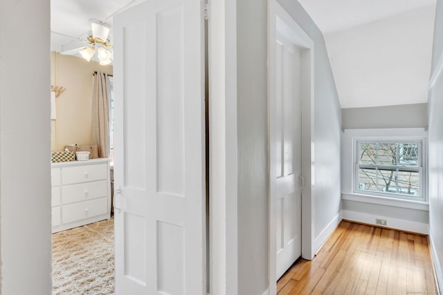 corridor with vaulted ceiling and light hardwood / wood-style floors