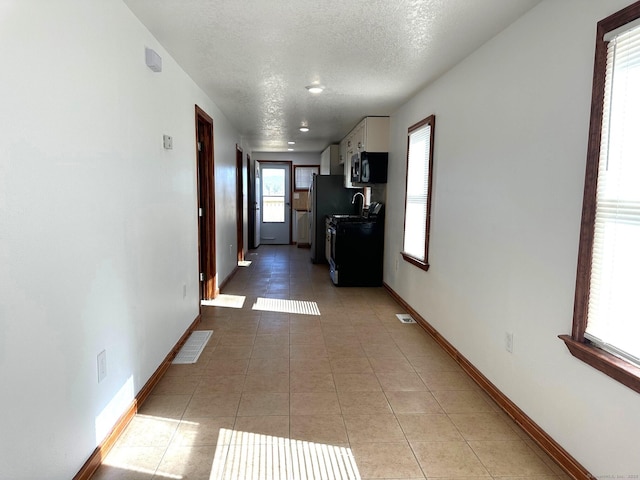 hallway featuring tile patterned floors and a textured ceiling