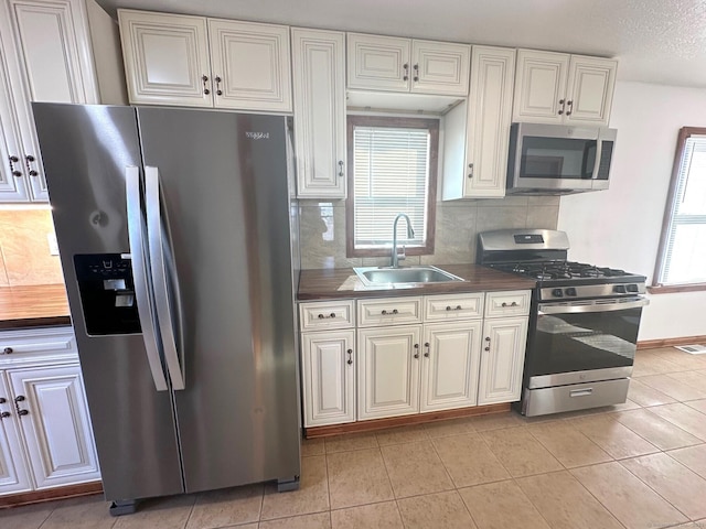 kitchen featuring stainless steel appliances, tasteful backsplash, sink, and white cabinets