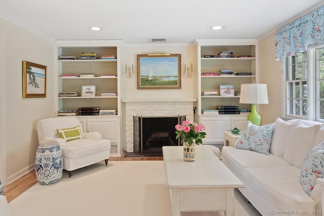 living area featuring light wood finished floors, built in features, crown molding, a fireplace, and recessed lighting